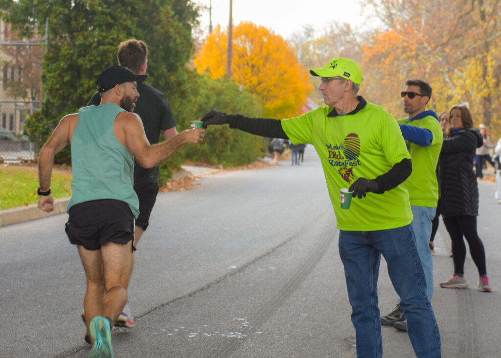 A volunteer handing a cup of water to a marathon runner at RaceFest
